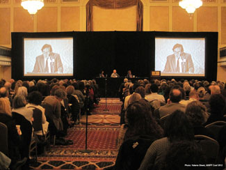 picture of conference hall with Stepehn Mitchell on screen